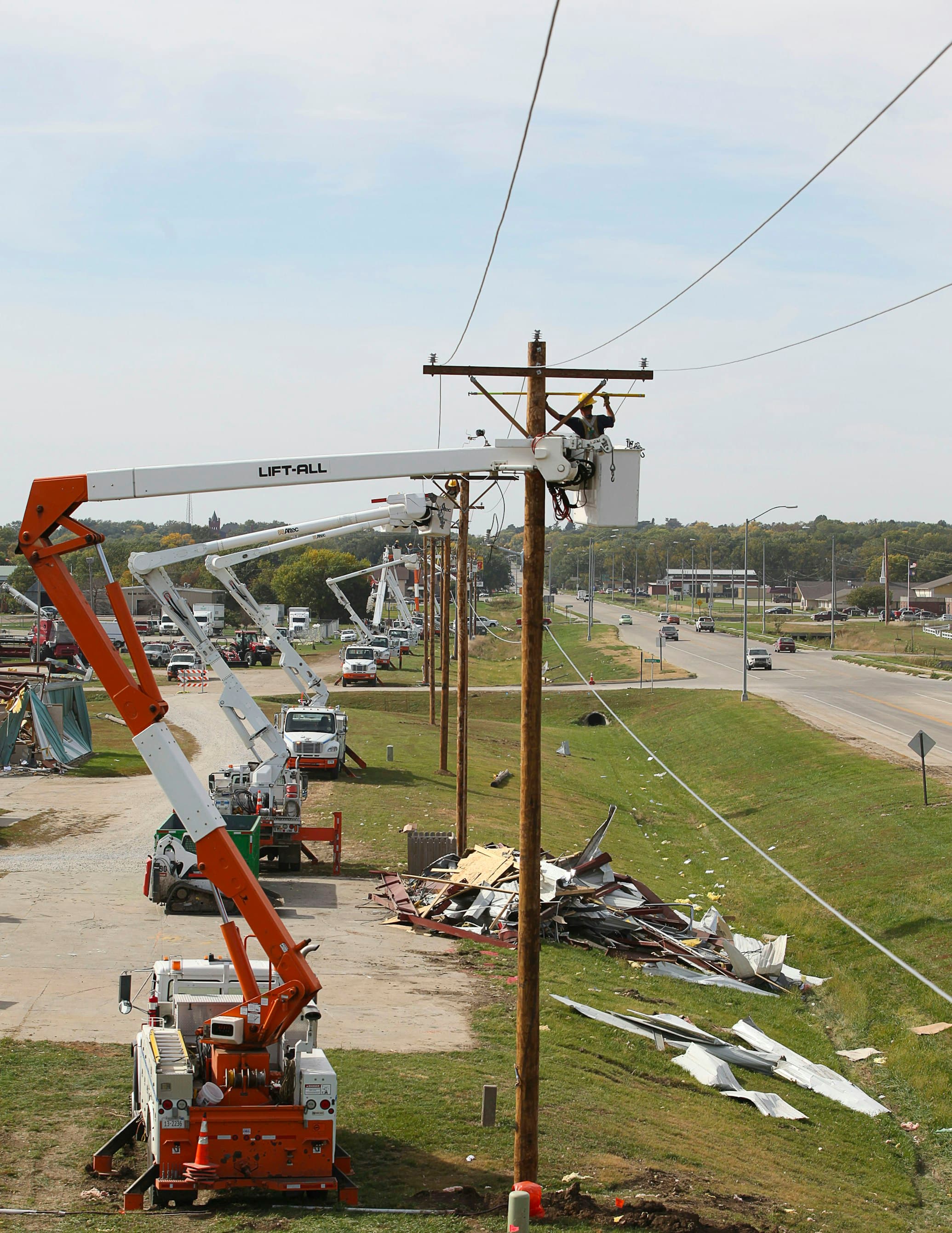 Crews staged with bucket trucks rebuilding line after storm damage